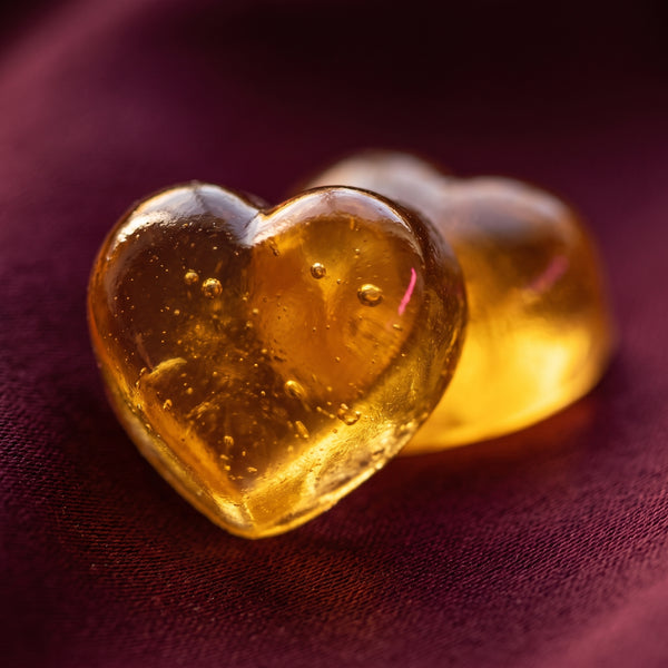 two golden heart gummies, glowing like amber